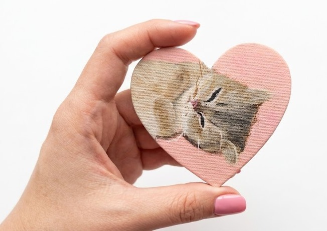 Herzförmiges kleines Gemälde: eine schlafende getigerte Katze auf rosa Grund, Acryl auf Leinwandtextur, in einer Hand gehalten.