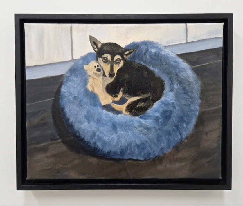 Acrylgemälde eines kleinen schwarz-braunen Hundes mit Kuscheltier in einem flauschigen hellblauen Hundekorb, schwarzer Schattenfugenrahmen.