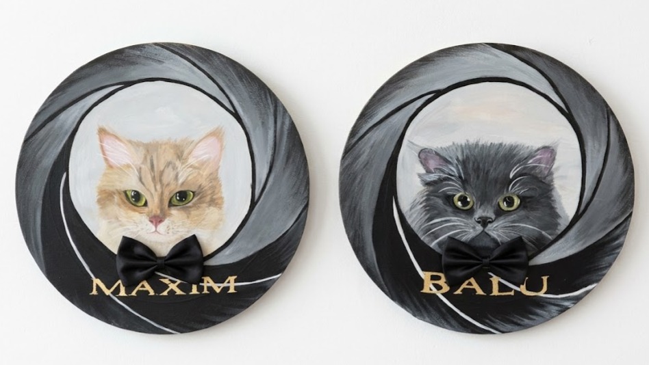 Zwei runde Gemälde nebeneinander: Porträts der Katzen Maxim und Balu mit Fliege im James-Bond-Fadenkreuz-Stil, Namen in Goldschrift.